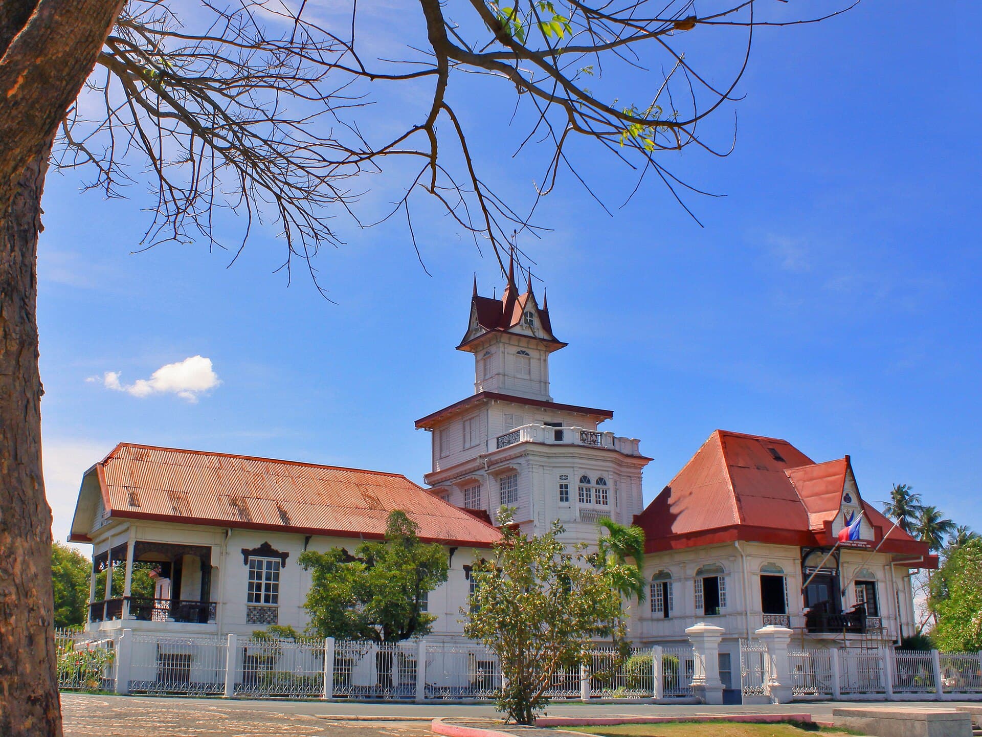 The white Aguinaldo Shrine in Kawit, with its tower, red roofs, and the Philippine flag.